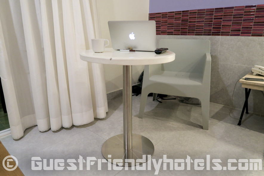 Small table with a plastic chair is found next to the balcony and bed in deluxe rooms of the Grand Bella Hotel Pattaya