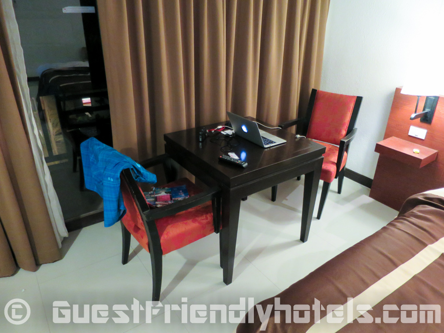 Table ans chairs next to the bed and balcony inside rooms of Patong Bay Garden Resort